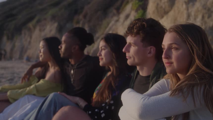 Group of friends sitting on the beach in the late afternoon