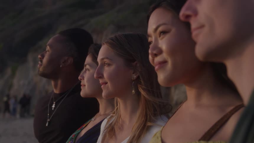 Friends smile while standing side by side on the beach