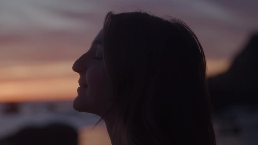 Woman in profile smiling serenely at sunset