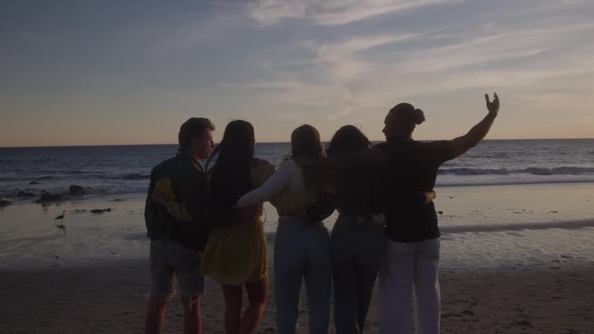 Group of friends hugging at dawn on the beach