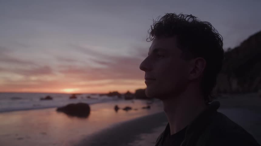 Young man enjoying the beach landscape in the late afternoon