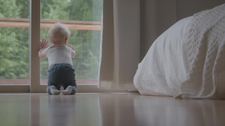 The baby crawls over to the window
