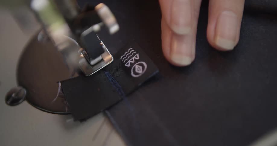 The woman feeds the fabric through the sewing machine