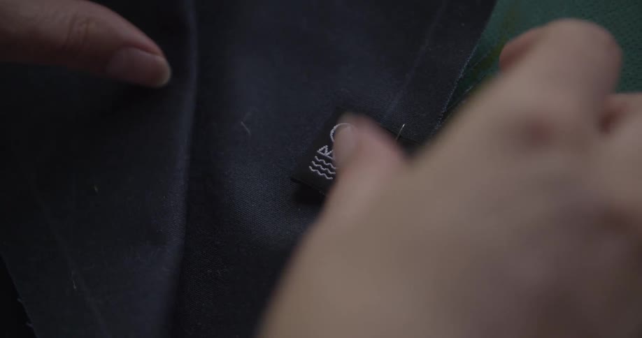 Hands are on a piece of fabric pinning a pin in place
