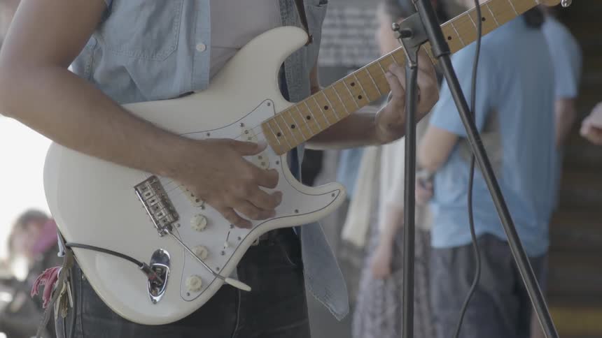 A guitarist plays on a stratocaster guitar
