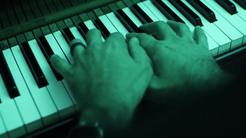 A persons hands move across the keys of a piano
