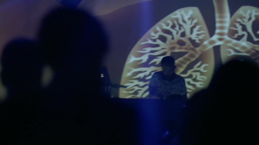 A dj is performing on stage with lights in the background