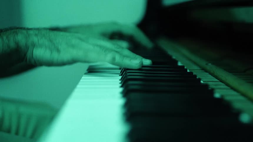 A persons hands move across the keys of a piano