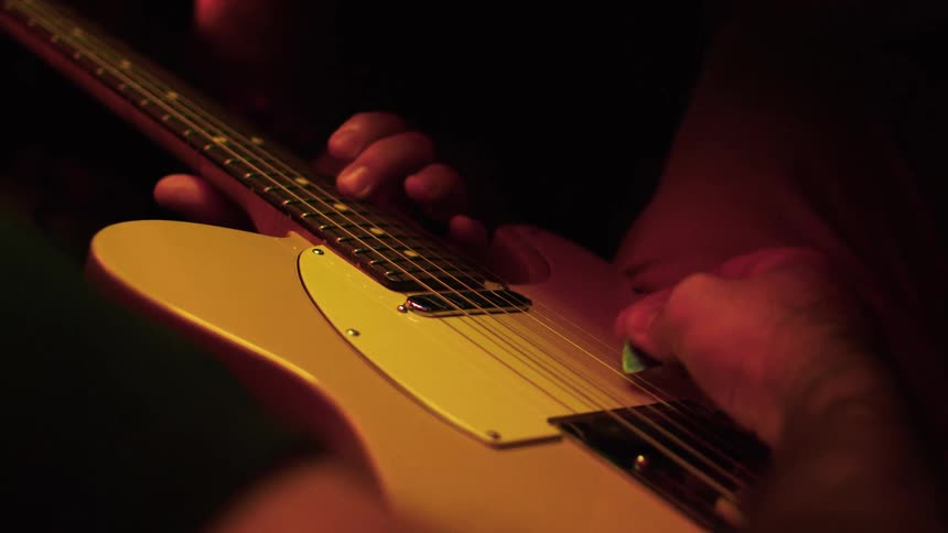 Mans hands playing an electric guitar on a studio setting