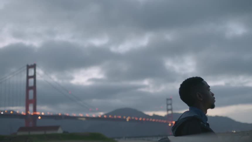 A man stares out near a bridge