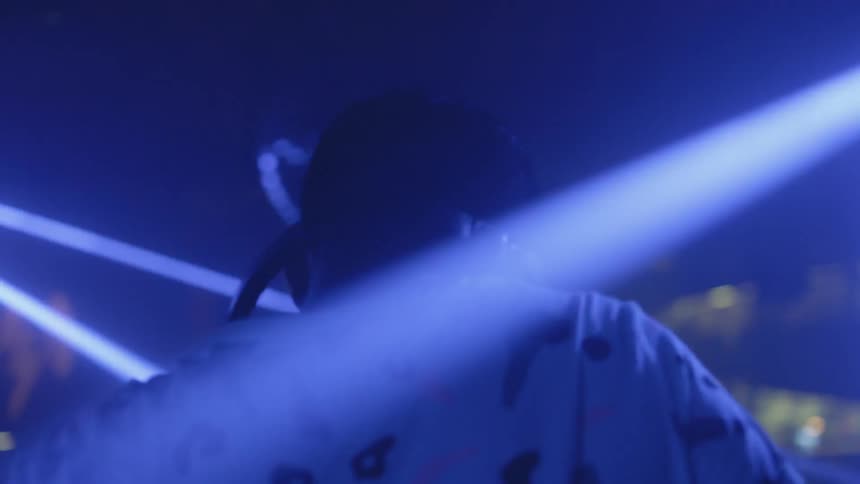 A dj plays in a club as lights strobe