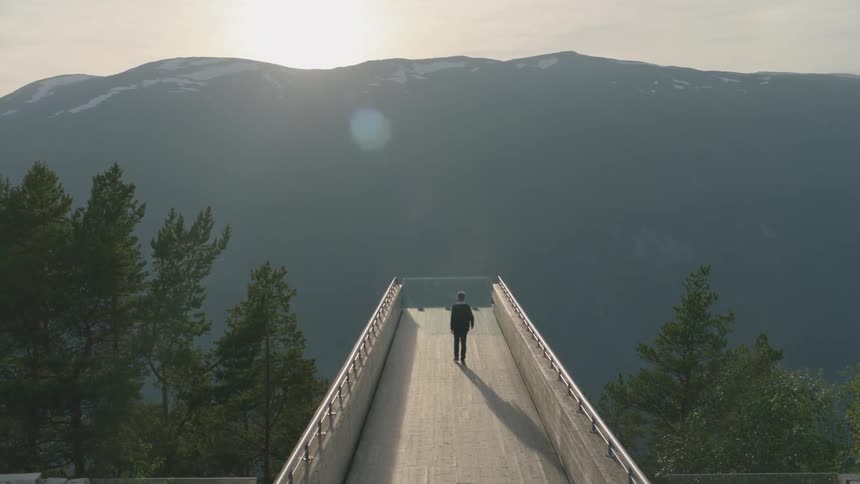 A man walks to the edge of the bridge
