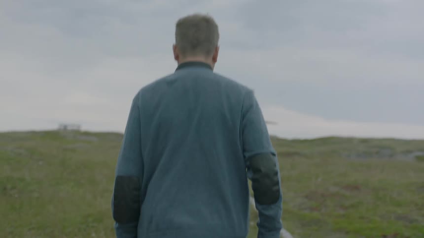 A man hikes up a grassy hill