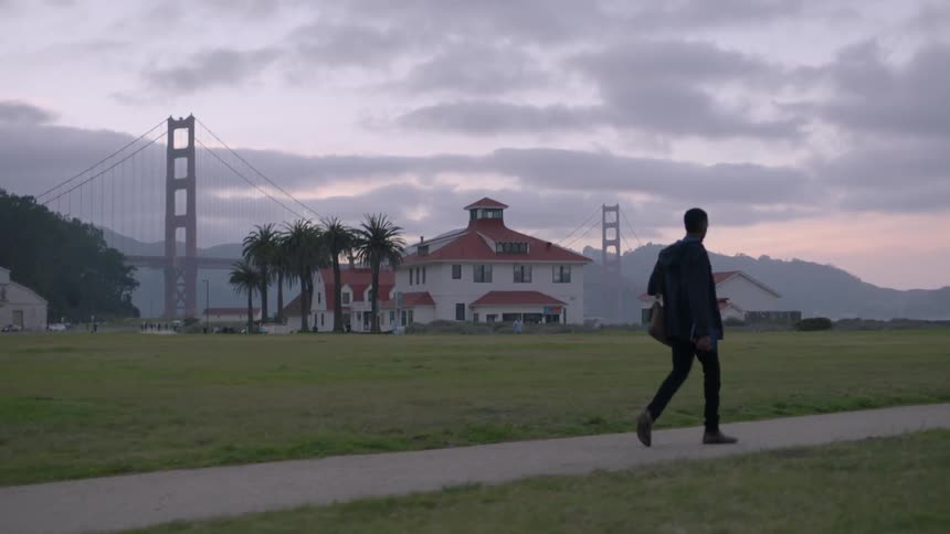 A man walks down a sidewalk near sunset