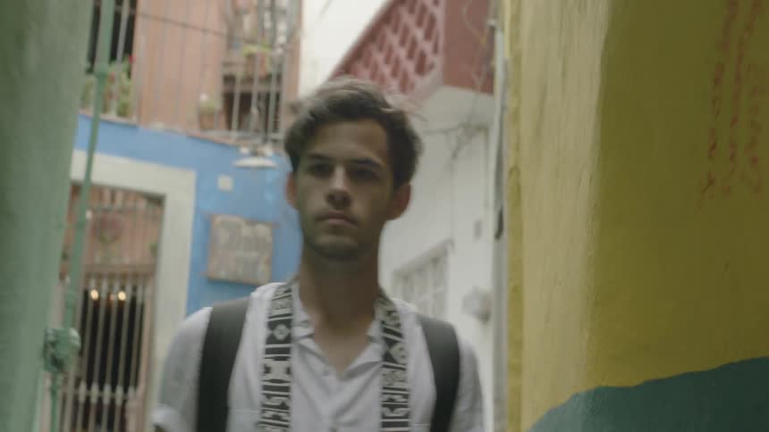A man walks down a slim alley