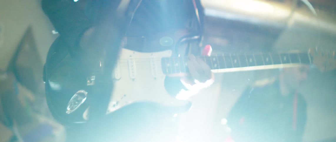 Two people in an indoor space playing guitar