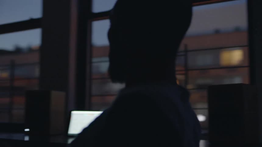 A man spins in a desk chair in a city apartment
