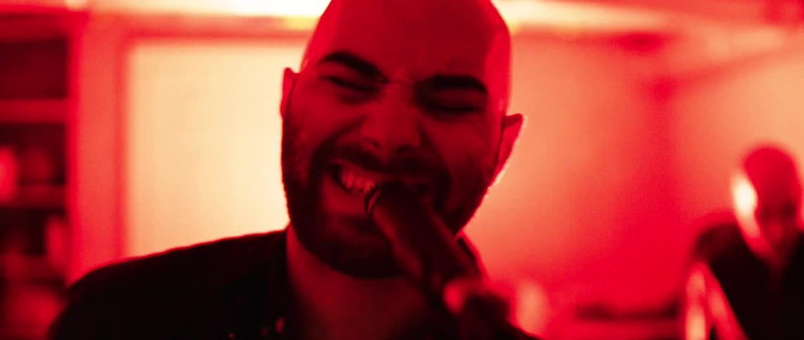 Male singer sings in a room lit by colored lights
