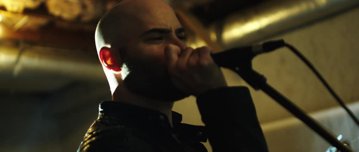 Man in a performance singing into a microphone in a vibrant way
