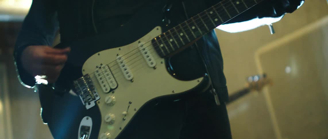 Guitarists play in a room with exposed rafters