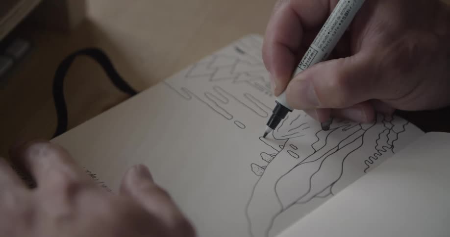 Person holding a pen and drawing in a book