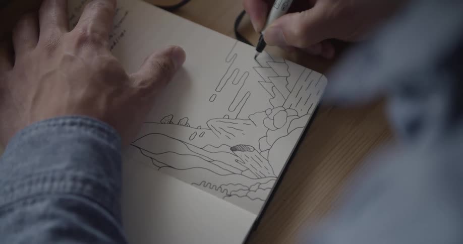 Hand sketches abstract landscape in open notebook