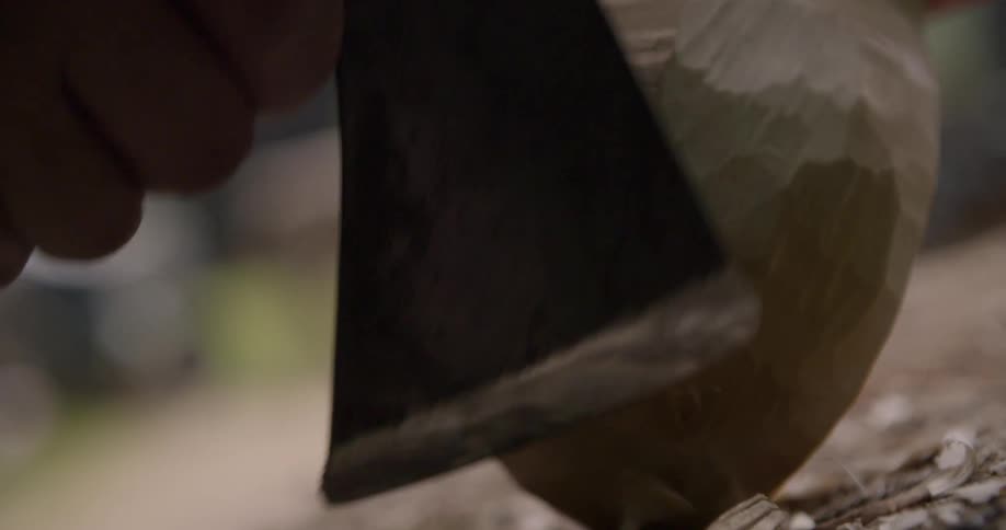 Man using an axe to carve wood at midday