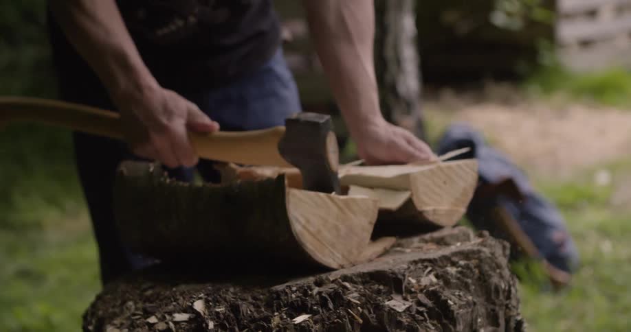 The man is cutting the small log in half