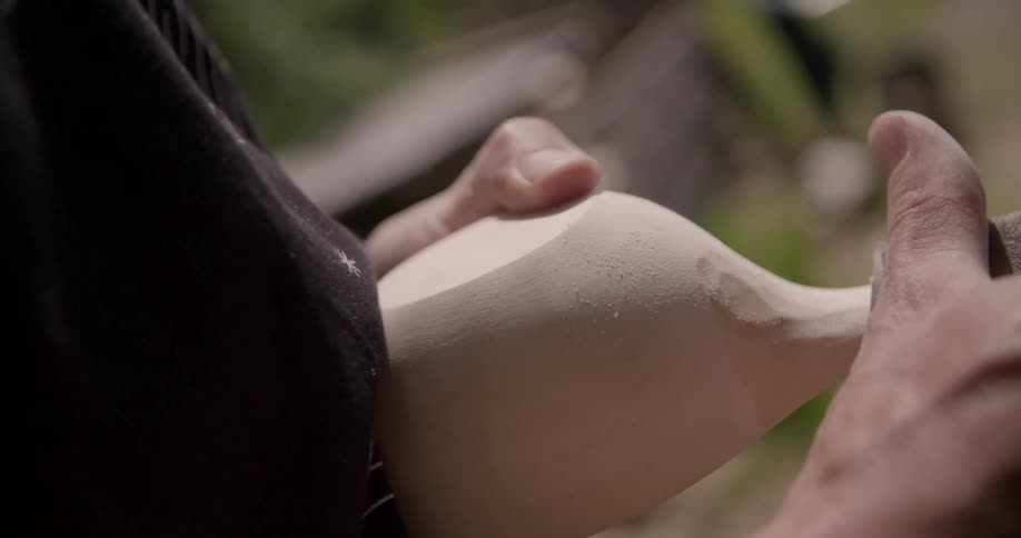 A persons hands diligently sand a wooden object creating fine dust that collects on its surface