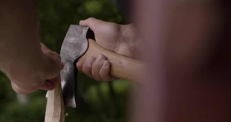 The man is carving wood with an ax