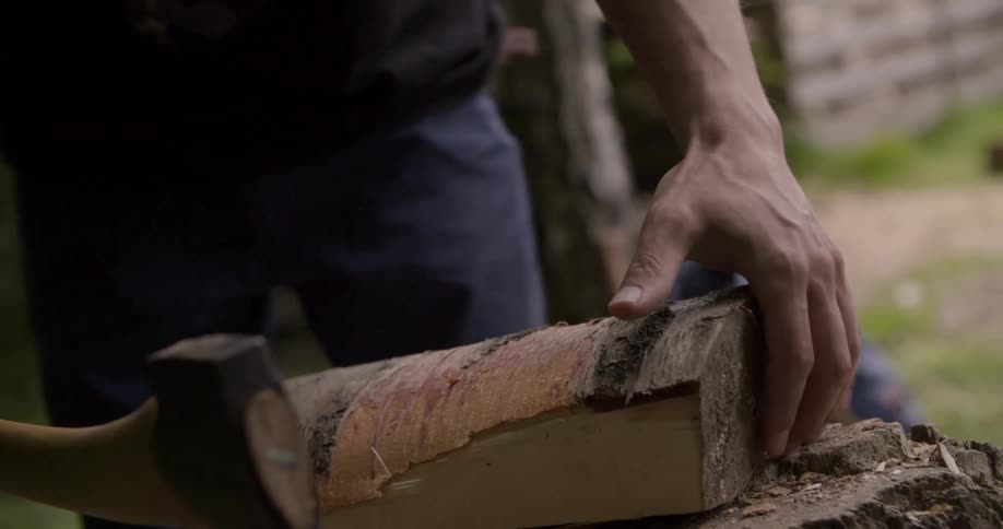 The man peels the bark off a log