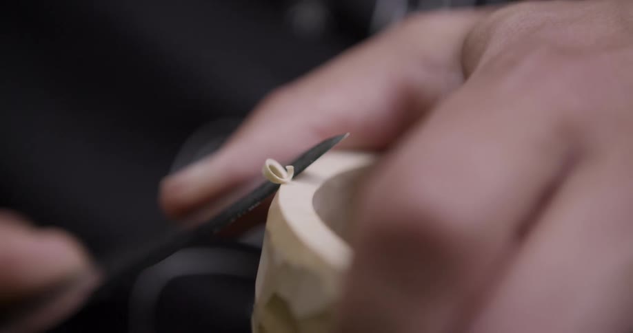 Hand carves wood with a pocket knife in closeup detail
