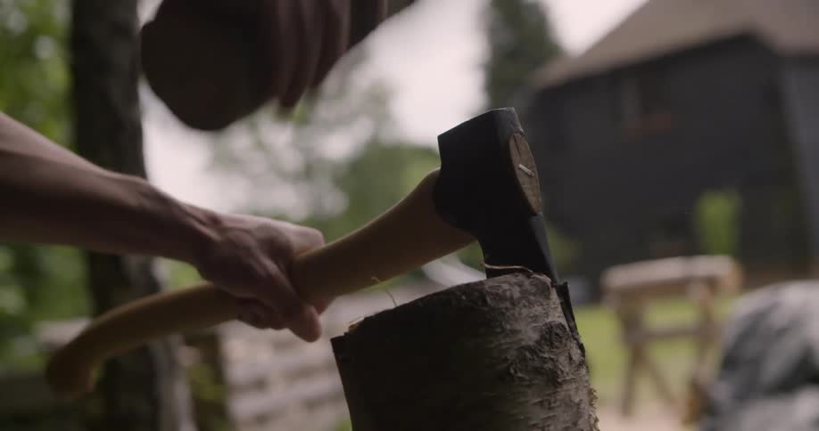 The man is driving an ax into a log with another log