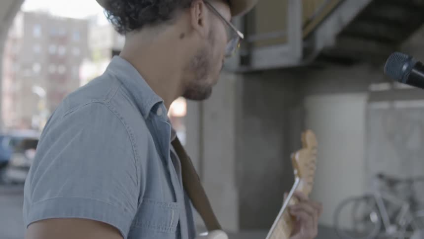 A man plays a guitar with a drummer nearby