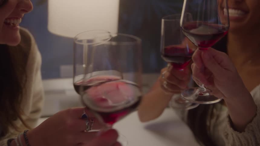 Four glasses of red wine clink together in closeup