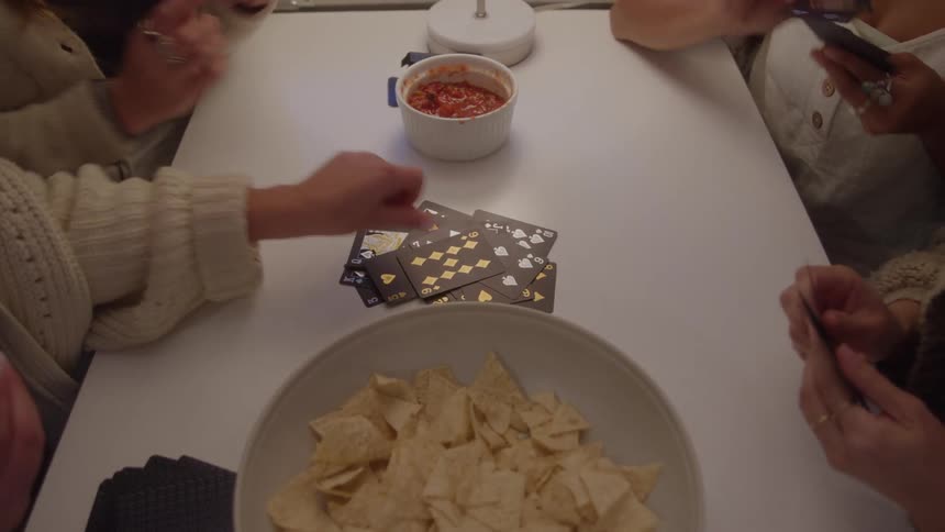 Women play cards with chips and salsa for a snack