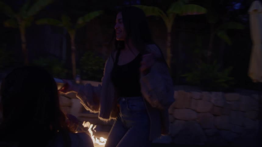 The woman brings snacks out to her friends by the fire pit
