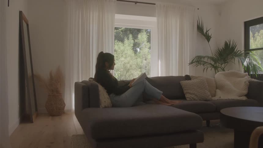 Woman sitting on the sofa in the living room reading a book
