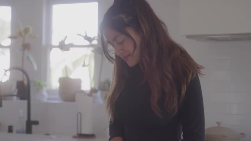 The woman is slicing vegetables in her kitchen