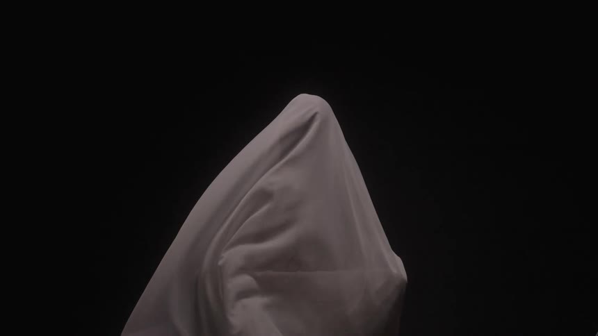 A persons body are covered by a thin white sheet as it moves with the wind