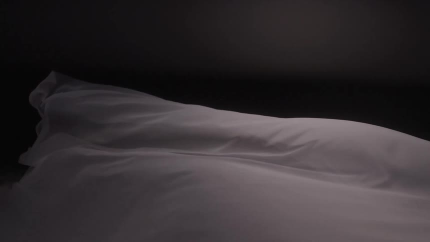 The sheet blows and flows in the dark