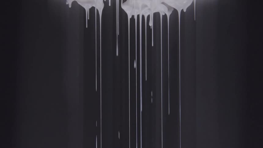 White paint dripping against a black background