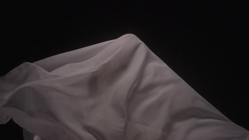 Figure of a person in a white fabric moving against a black background