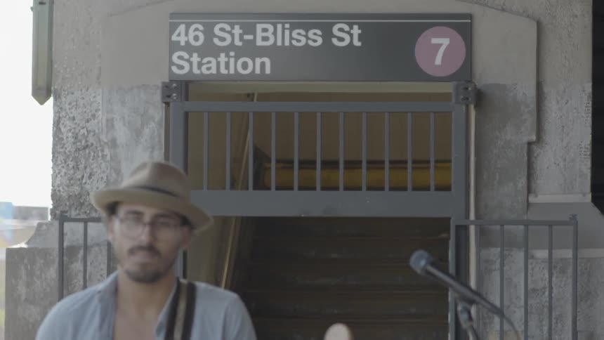 A man plays guitar in front of a subway station entrance