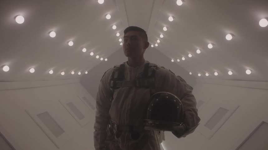 Man in spacesuit in a white lit corridor