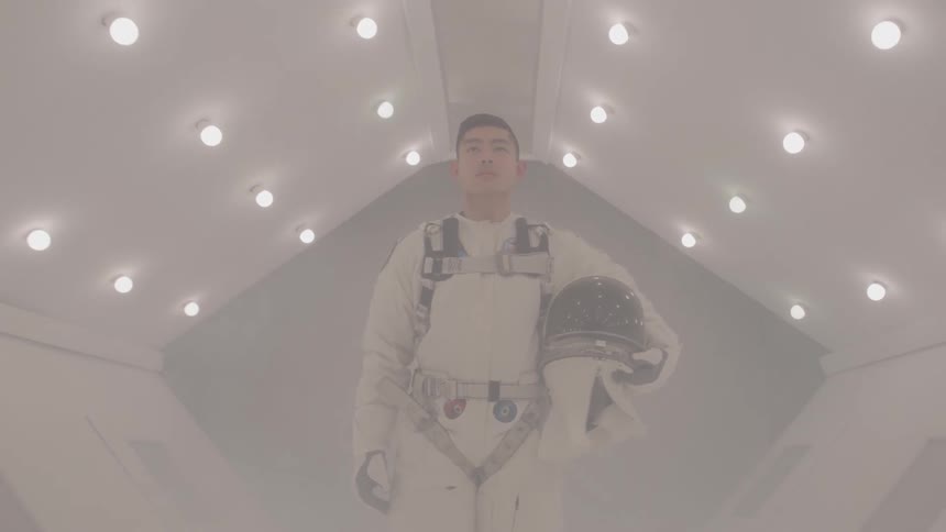 A male astronaut in a white suit is standing in a brightly lit sterilelooking corridor holding his helmet the lighting gives the scene a futuristic scifi feel and the astronaut looks determined as he walks towards the camera