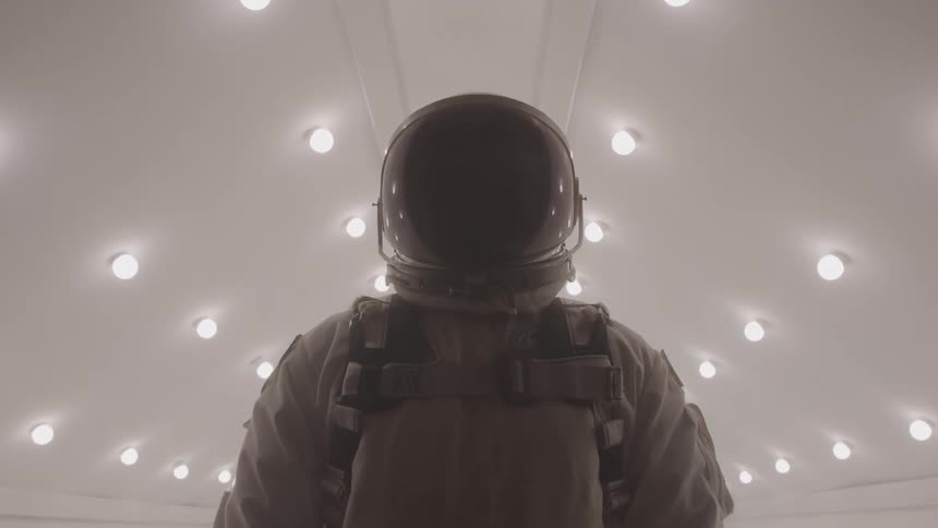 Person in spacesuit in a lit hallway