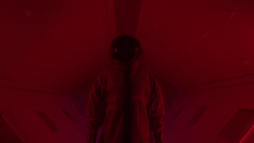 Static person in spacesuit in a corridor with dim lights