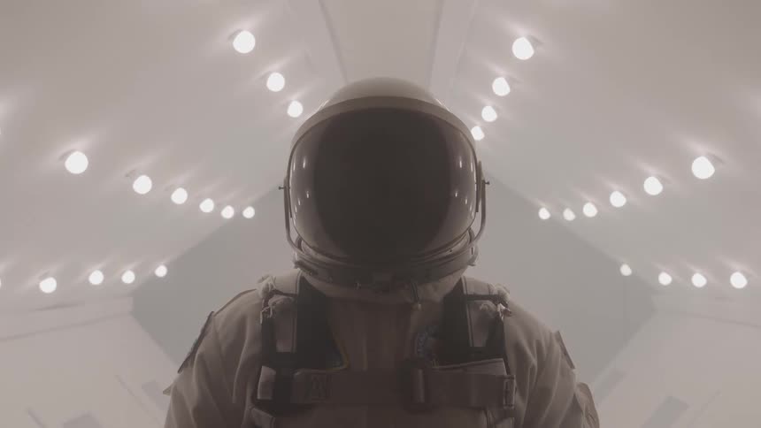 The astronaut stands in the brightly lit corridor