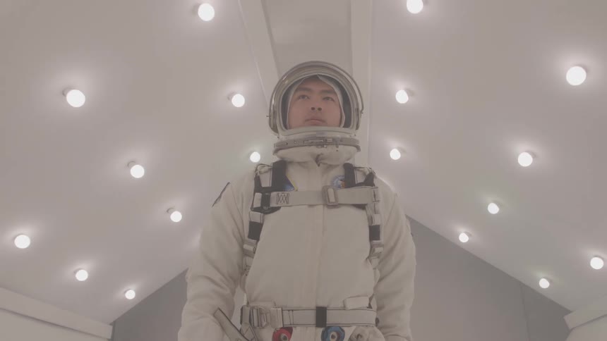 Astronaut in white suit stands under illuminated ceiling